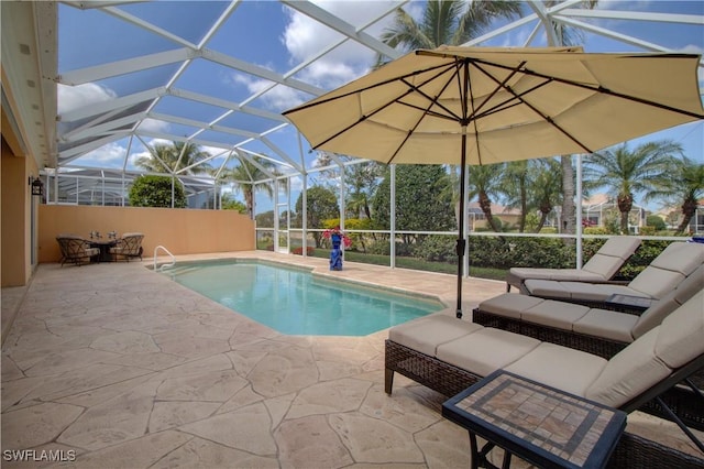 outdoor pool featuring a patio area, glass enclosure, and an outdoor hangout area