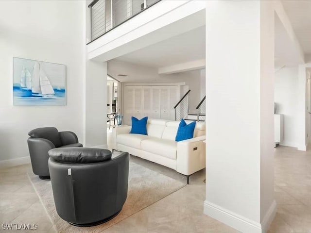 living room featuring a high ceiling and baseboards