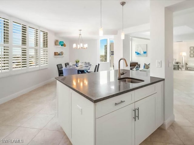 kitchen with light tile patterned floors, an inviting chandelier, hanging light fixtures, white cabinetry, and a sink