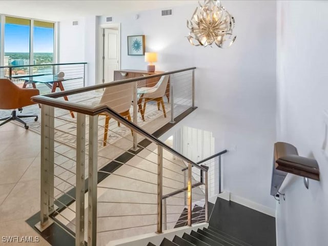 stairway featuring visible vents, baseboards, a chandelier, and floor to ceiling windows