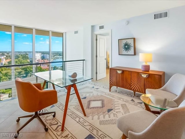 living area featuring tile patterned floors, visible vents, and expansive windows