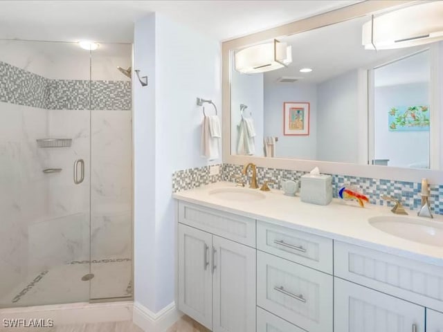 bathroom featuring a sink, a marble finish shower, backsplash, and double vanity