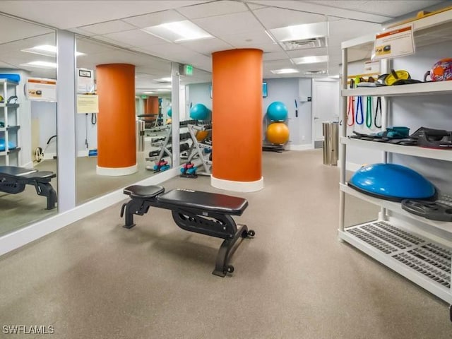 workout area with visible vents, a paneled ceiling, and baseboards