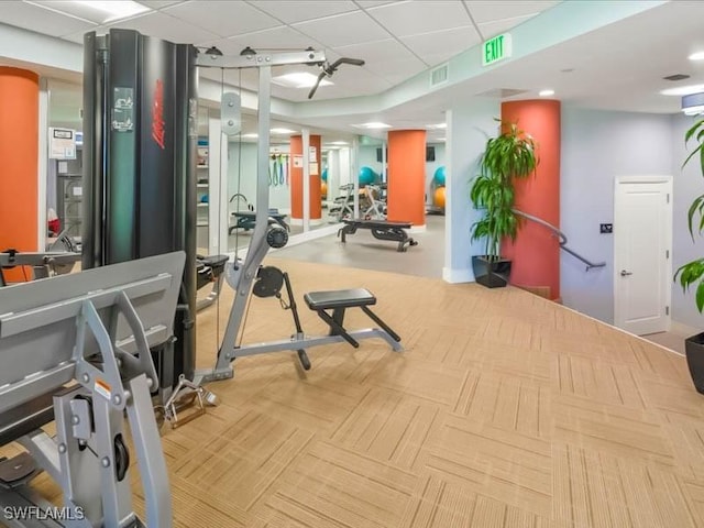 exercise room featuring a paneled ceiling, visible vents, and carpet flooring