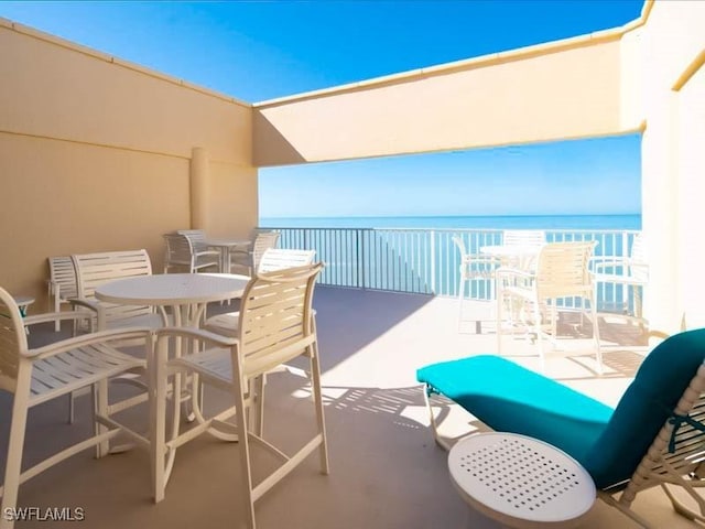 balcony featuring a water view and outdoor dining space