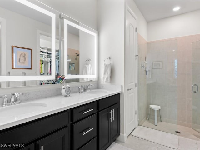 bathroom featuring double vanity, a shower stall, tile patterned floors, and a sink