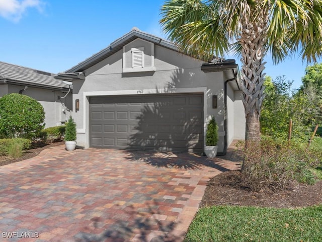 exterior space with stucco siding, decorative driveway, and an attached garage