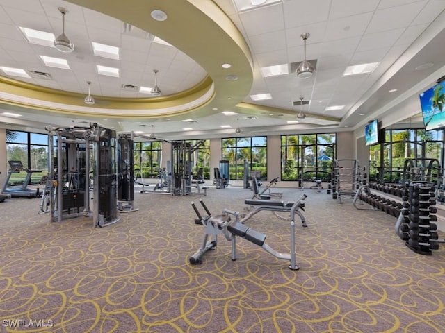 exercise room with a tray ceiling, carpet, visible vents, and a paneled ceiling