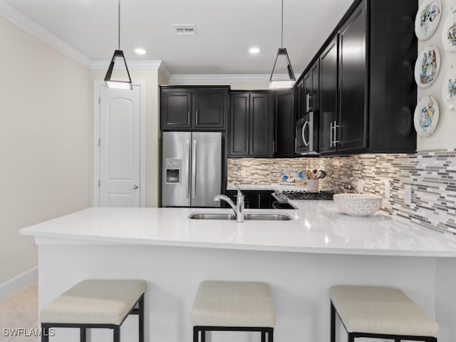 kitchen with visible vents, a sink, dark cabinetry, stainless steel appliances, and decorative backsplash