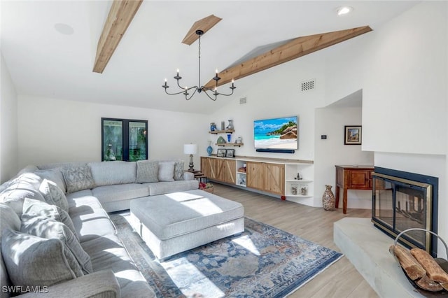 living area with beamed ceiling, visible vents, a notable chandelier, a glass covered fireplace, and light wood-style floors