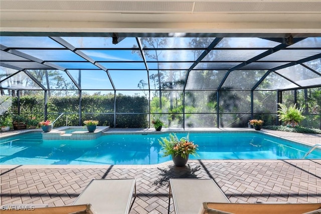 view of swimming pool featuring glass enclosure, a patio area, and a pool with connected hot tub