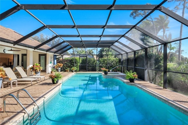 view of pool with glass enclosure, a pool with connected hot tub, and a patio area