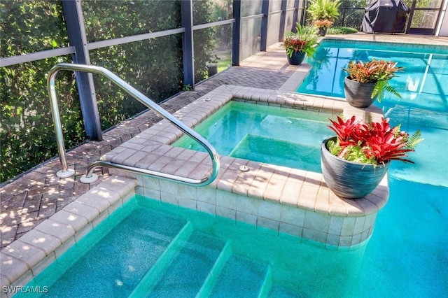 pool with glass enclosure, an in ground hot tub, and a grill