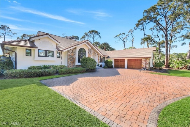 view of front of home with stucco siding, a front lawn, decorative driveway, a garage, and a tiled roof