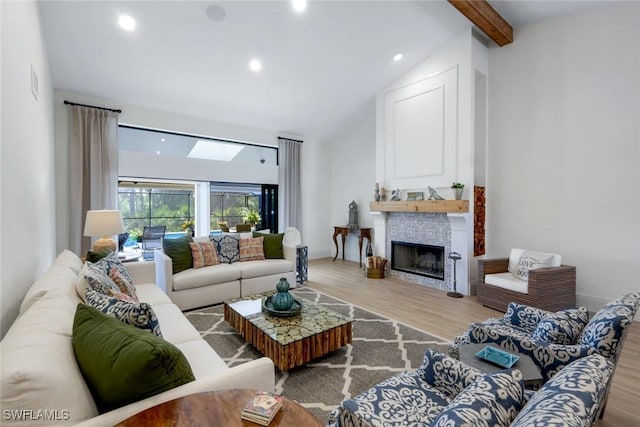 living room featuring beam ceiling, a tile fireplace, high vaulted ceiling, and wood finished floors