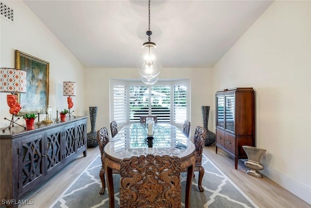 dining space featuring lofted ceiling, light wood-style flooring, baseboards, and visible vents