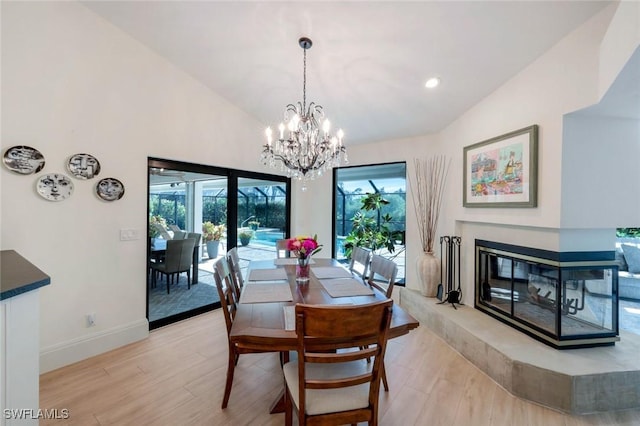 dining area with baseboards, light wood finished floors, high vaulted ceiling, recessed lighting, and a multi sided fireplace