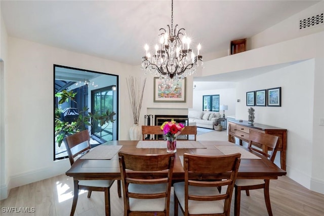 dining space featuring light wood-style flooring, a fireplace, visible vents, and a wealth of natural light