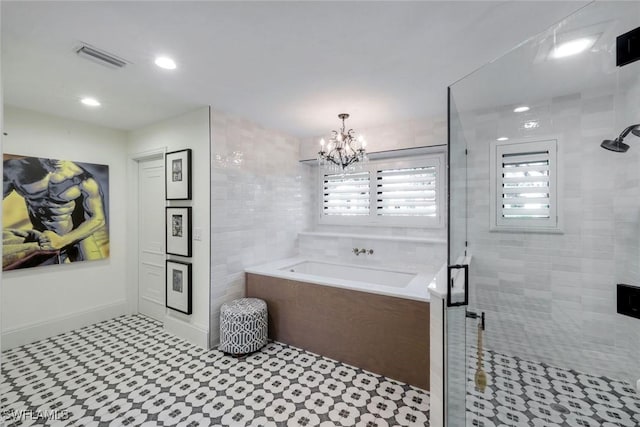 full bathroom featuring a chandelier, visible vents, a stall shower, and a garden tub