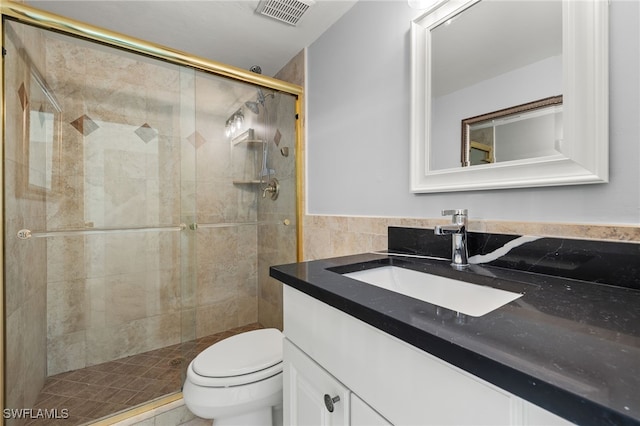 full bathroom with visible vents, toilet, vanity, a stall shower, and tile walls