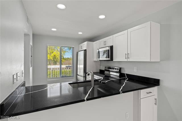 kitchen with dark countertops, recessed lighting, white cabinetry, and stainless steel appliances