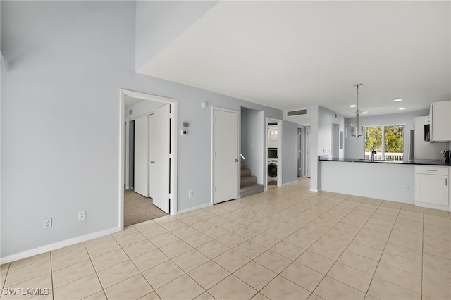 unfurnished living room featuring stairway, baseboards, visible vents, washer / clothes dryer, and a sink