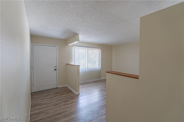 entrance foyer featuring baseboards, a textured ceiling, and wood finished floors