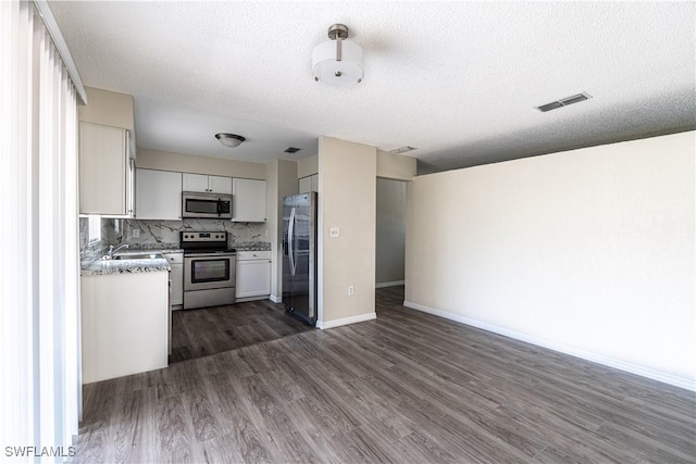 kitchen featuring visible vents, dark wood finished floors, stainless steel appliances, tasteful backsplash, and open floor plan