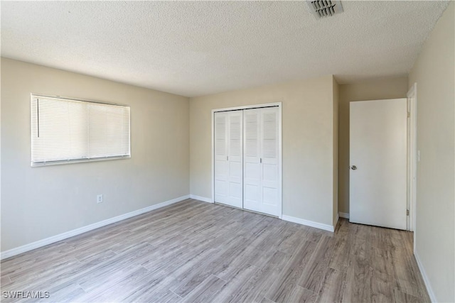 unfurnished bedroom featuring light wood-style floors, visible vents, a closet, and baseboards