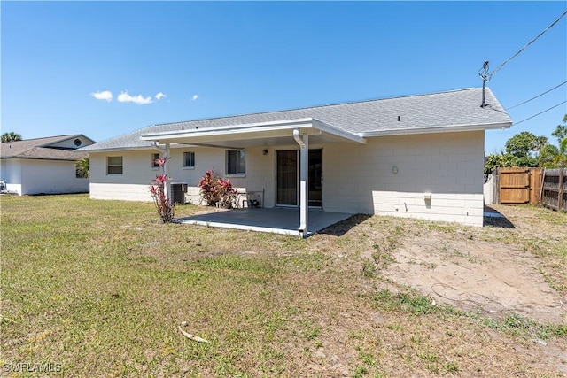 back of house with concrete block siding, cooling unit, fence, a yard, and a patio area