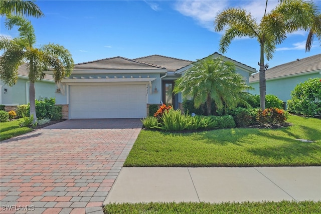 view of front of home featuring stucco siding, a tile roof, decorative driveway, a front yard, and a garage