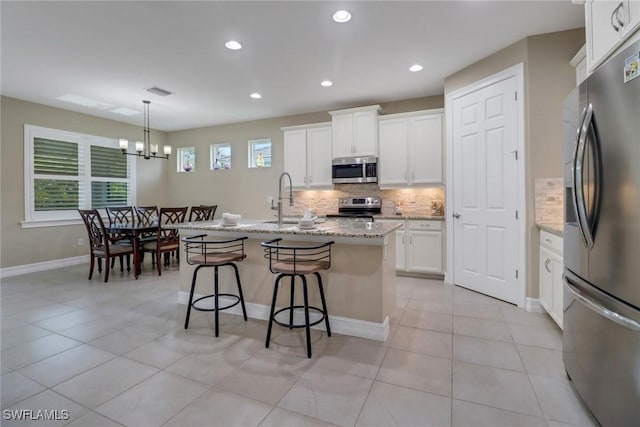 kitchen featuring a sink, tasteful backsplash, stainless steel appliances, a breakfast bar area, and light tile patterned floors