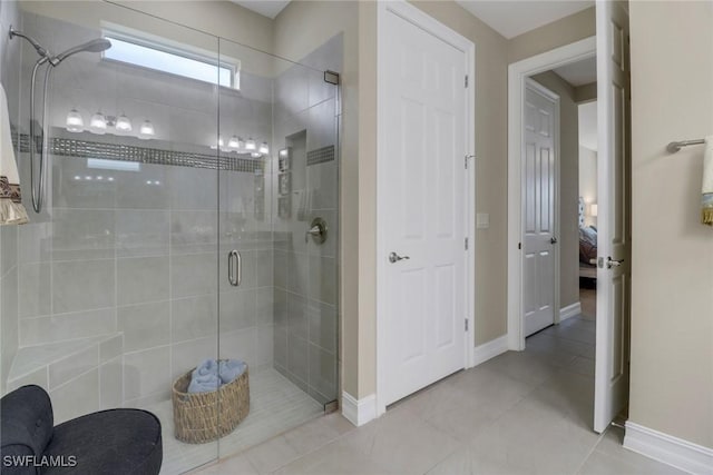 ensuite bathroom featuring tile patterned flooring, a shower stall, baseboards, and connected bathroom