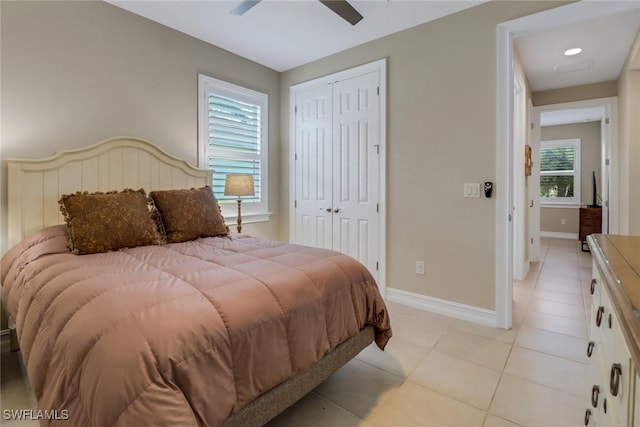 bedroom featuring a ceiling fan, light tile patterned floors, baseboards, and a closet