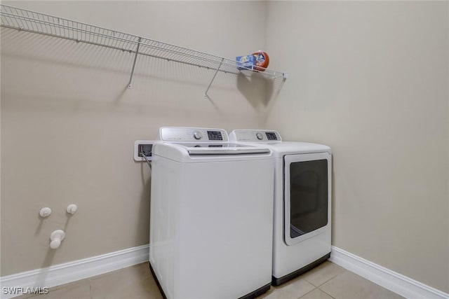 laundry room with laundry area, light tile patterned flooring, baseboards, and independent washer and dryer