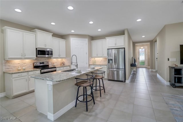 kitchen featuring a sink, appliances with stainless steel finishes, an island with sink, and white cabinetry