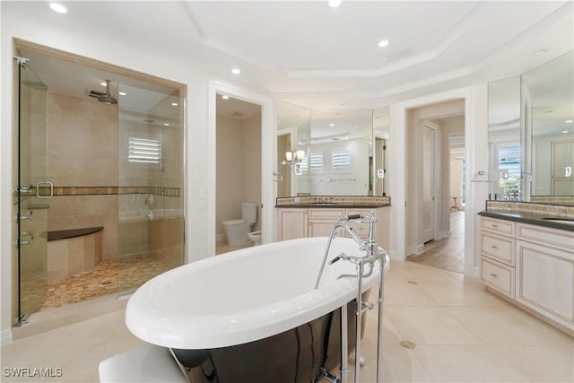 full bathroom with a shower stall, a freestanding bath, toilet, a tray ceiling, and tile patterned floors