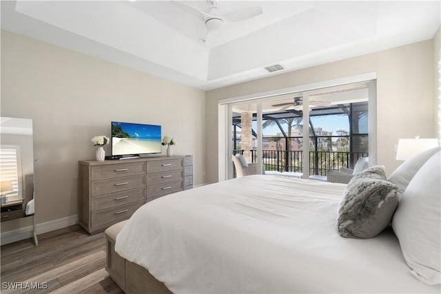 bedroom with visible vents, access to outside, wood finished floors, baseboards, and a raised ceiling