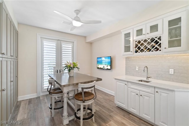 interior space featuring backsplash, white cabinetry, light wood-style floors, and a sink