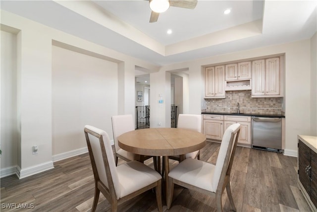 dining space with dark wood-style floors, a raised ceiling, and baseboards