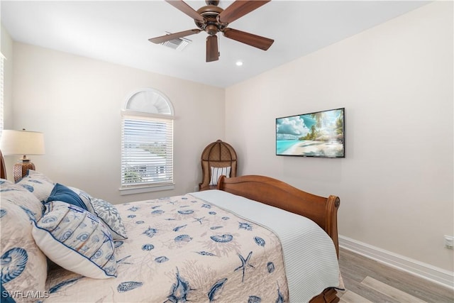 bedroom featuring wood finished floors, baseboards, visible vents, and ceiling fan