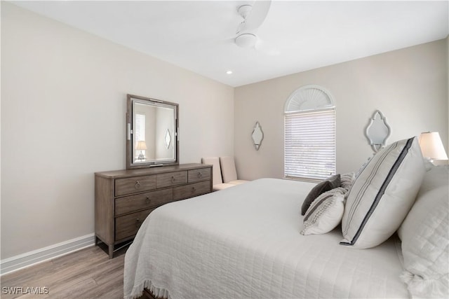 bedroom featuring light wood finished floors, multiple windows, a ceiling fan, and baseboards