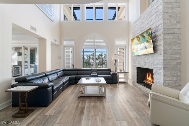 living area featuring visible vents, a stone fireplace, and light wood finished floors