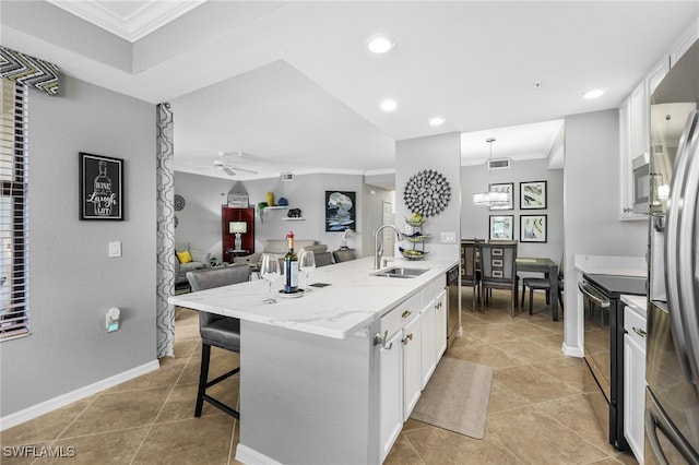 kitchen with open floor plan, ornamental molding, appliances with stainless steel finishes, white cabinets, and a sink