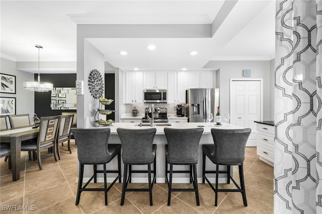 kitchen featuring tasteful backsplash, appliances with stainless steel finishes, ornamental molding, and a breakfast bar