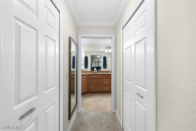 hall with light carpet, ornamental molding, and a textured wall