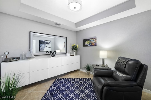 sitting room with visible vents, a raised ceiling, baseboards, and tile patterned flooring