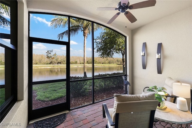 sunroom / solarium featuring a water view and a ceiling fan