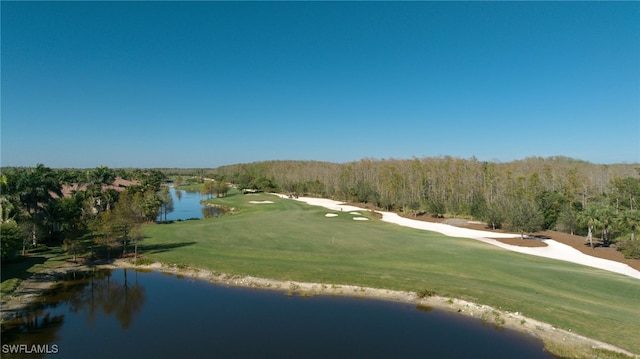 view of community featuring view of golf course, a lawn, a water view, and a wooded view