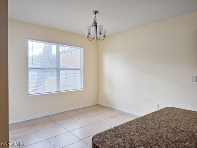 unfurnished dining area featuring light tile patterned flooring, baseboards, and a chandelier